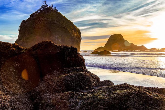 Bright sun in late afternoon on rocky beach with sun flare