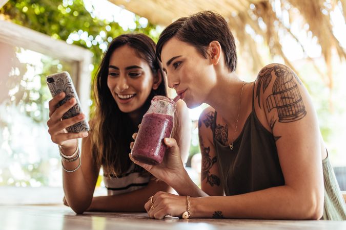 Close up of two females sitting at a restaurant looking at mobile phone