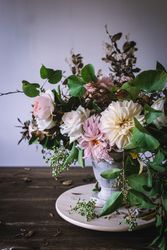 Composition of flowers and plants in vintage vase on board