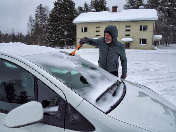 Man scraping ice off windscreen of vehicle