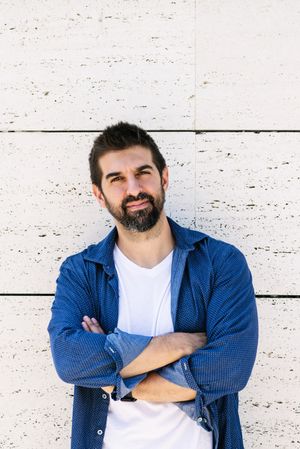 Serious man in denim standing outside with arms crossed