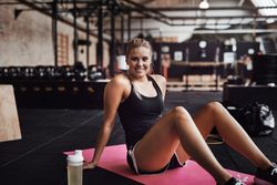 Woman smiling on yoga mat in weightlifting gym