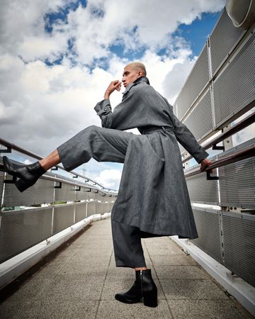 Stylish young man with leg up on handrail on walkway