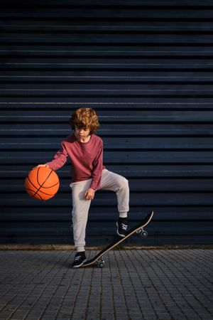 Little skater playing basketball on street