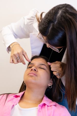 Beautician doing eyebrow threading design procedure