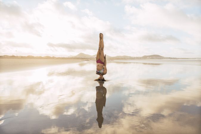 Woman doing handstand near sea