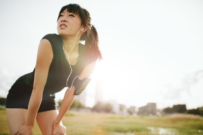Young Asian woman leaning over in sports gear