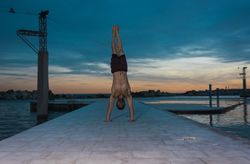 Athletic man balancing on hands on embankment