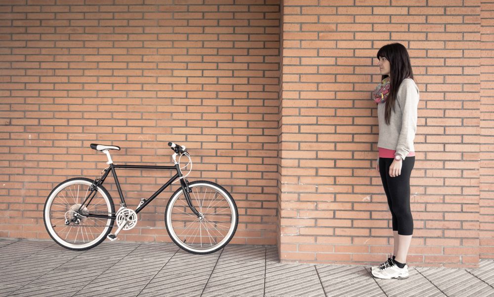 Sportive woman with fixie bike over a brick wall