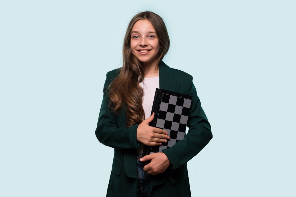 Teen girl smiling while holding a chessboard