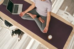Unrecognizable woman practicing yoga with beer near laptop