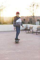 Teenager skateboarder riding on asphalt in playground at sunset