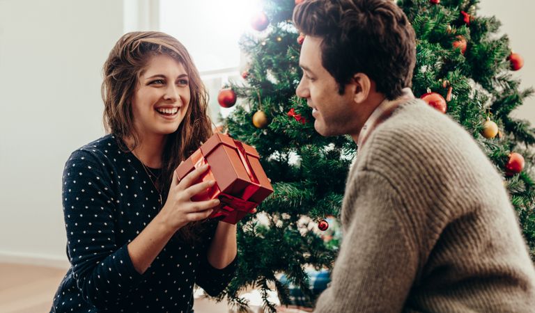 Man and woman exchanging Christmas presents in their living room