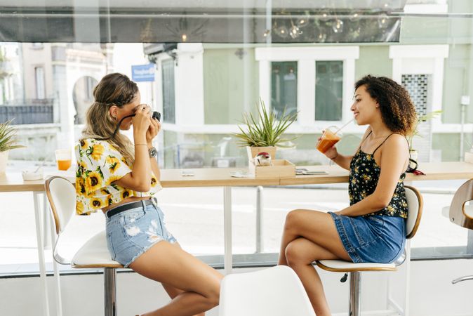 Woman taking photo of friend in cafe