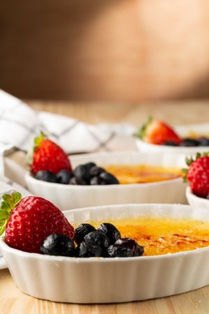 Side view of creme brûlée with berries on wooden table