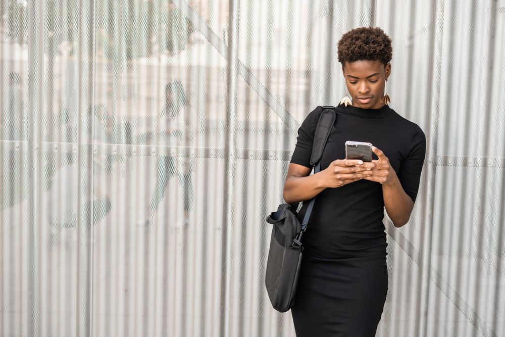 Concentrated female using mobile near urban building