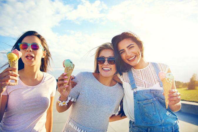 Smiling female friends enjoying ice cream in the sun