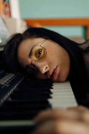 Young woman in sunglasses lying on piano