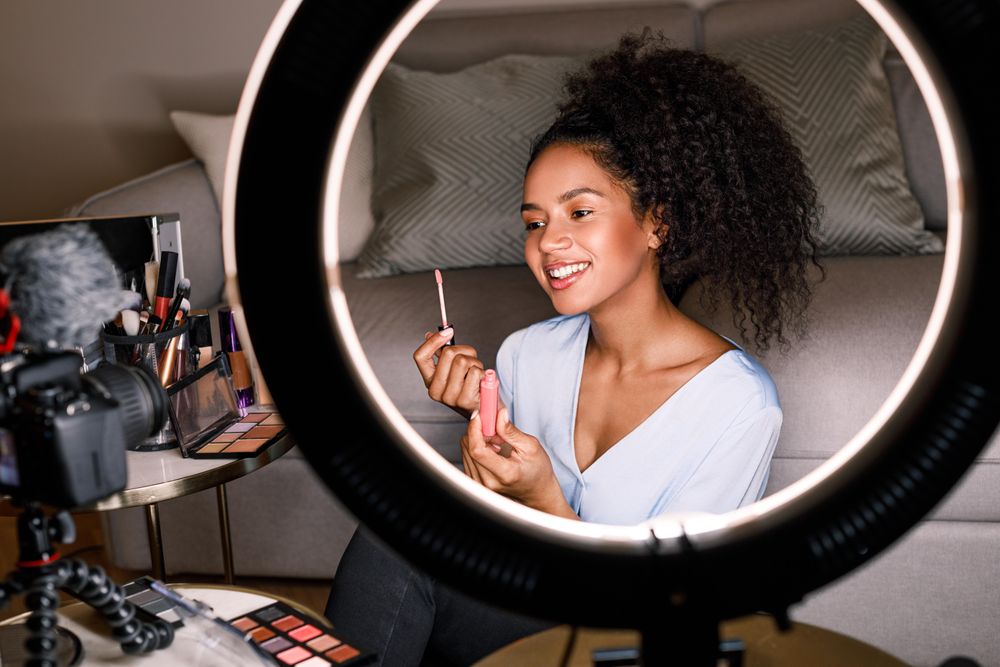 Woman pictured using light ring demoing lip gloss