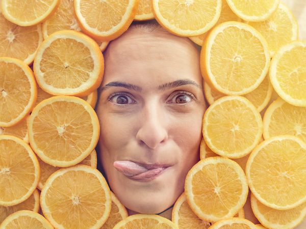 Funny woman covered in orange slices showing tongue