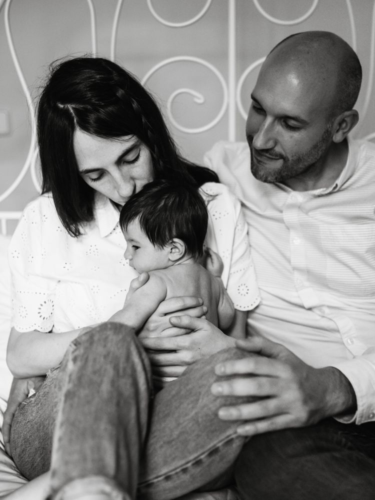 Parents hugging baby on bed