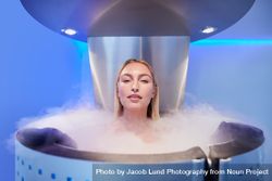 Blonde woman standing in cryotherapy chamber 5XrKzr