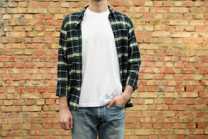 Men in t-shirt and checkered shirt against brick wall, copy space