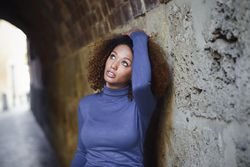 Woman with curly hair looking up and touching her hair standing in European street