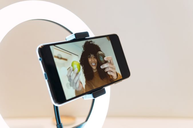 Cheerful Black women filming blog on smartphone