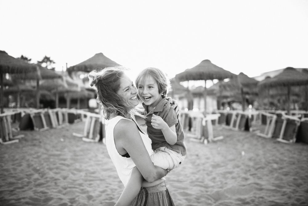 Woman with naughty boy on hands on beach