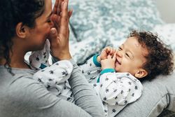 Mother playing peek-a-boo with her giggling son