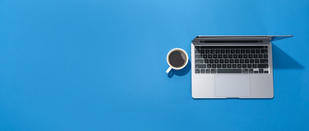 Banner of blue room with laptop with coffee with blank screen