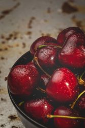 Juicy red cherry in bowl on rustic surface