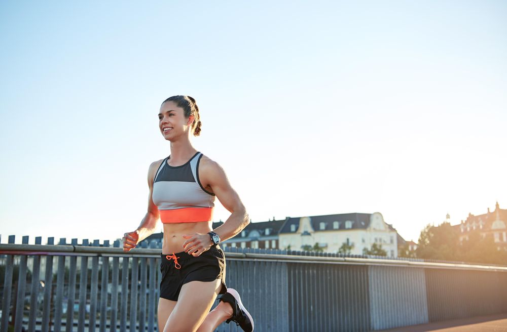 Muscular smiling woman running outside