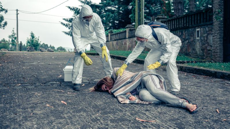 Doctors in protection suits caring for a woman
