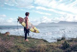 Fit bearded guy with surfboard standing at seaside