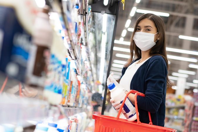 Woman picking up items at grocery shopping in surgical mask