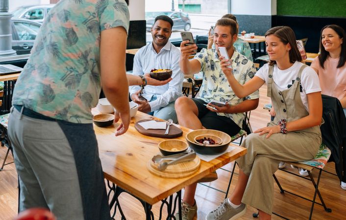 Chef serving exotic dish to food bloggers taking pictures during cooking master class