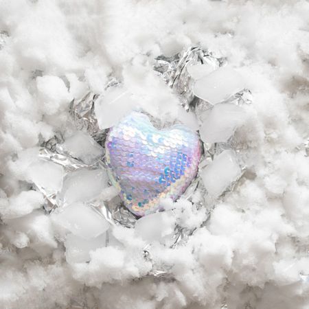 Heart in iridescent sequins on snowy and silver background
