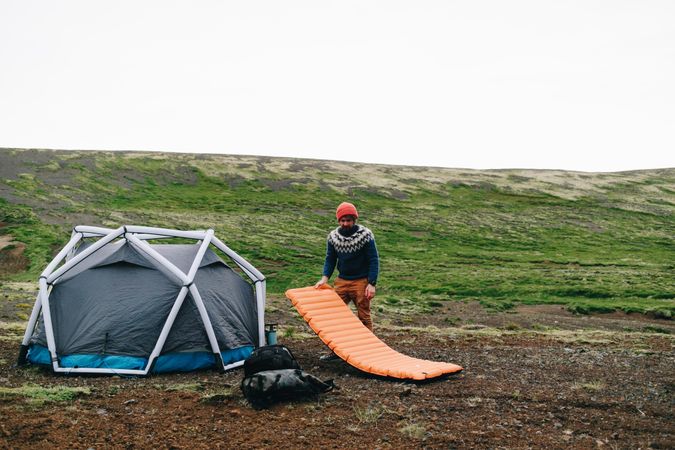 Man setting up bed tent in field