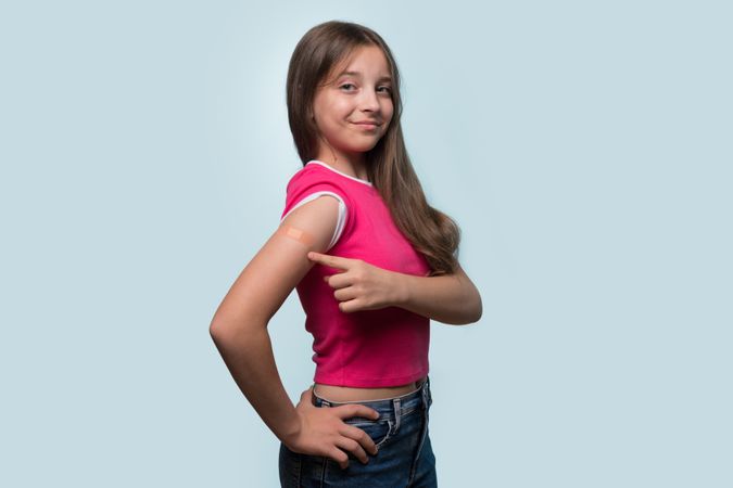 Girl points to arm after receiving vaccination shot.