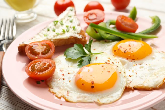Two fried eggs and toast on pink plate