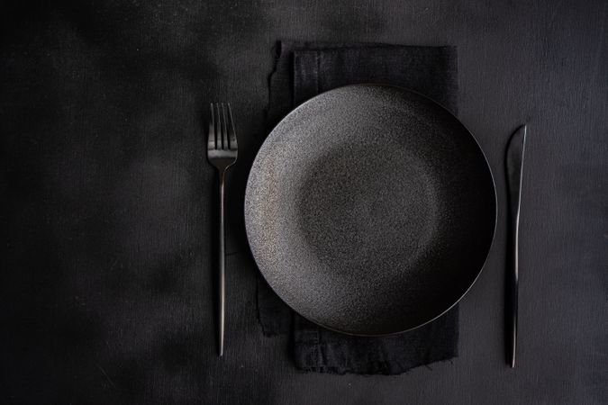 Table setting with dark plate, napkin and silverware