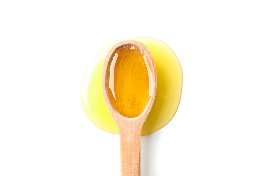 Wooden spoon with honey isolated on blank background, top view