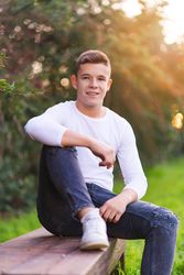 Smiling teenager sitting on park bench looking at camera