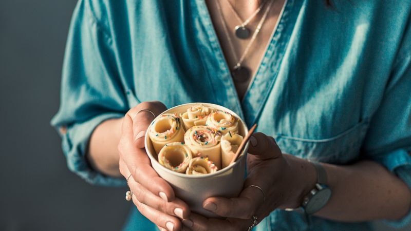 Hand holding rolled ice cream in cone cup