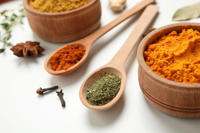 Wooden spoons and bowls filled with colorful spice