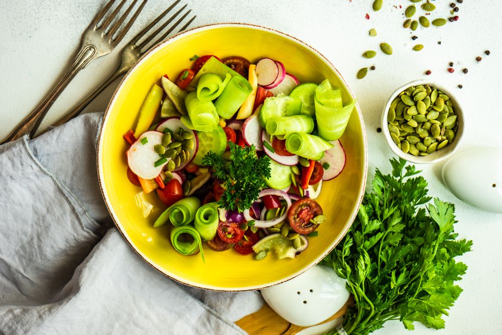 Top view of raw salad with chopped vegetables served with nuts and garnish