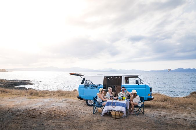 group of friends sitting in chairs next to a minivan