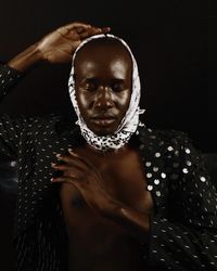 Bare-chested man wearing dark polka top and headscarf closing his eyes